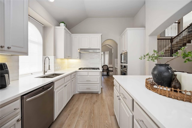 30427 Legacy Pines Dr, Spring, TX 77386 - kitchen with appliances with stainless steel finishes, a sink, light wood-style floors, white cabinets, and vaulted ceiling