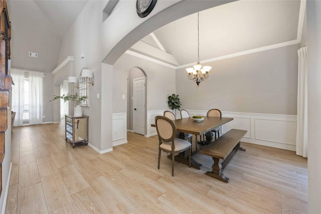 30427 Legacy Pines Dr, Spring, TX 77386 - dining room with a chandelier, arched walkways, high vaulted ceiling, wainscoting, and light wood-style flooring