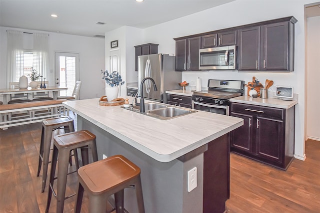 kitchen with stainless steel appliances, a sink, dark wood-type flooring, a breakfast bar area, and recessed lighting