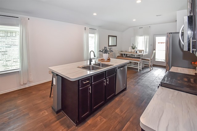 kitchen with a sink, stainless steel dishwasher, dark wood-style floors, light countertops, and an island with sink