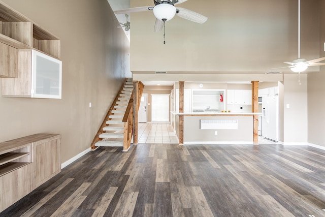44 April Point Dr S, Montgomery, TX 77356 - unfurnished living room featuring ceiling fan, baseboards, light wood-style flooring, stairway, and a towering ceiling