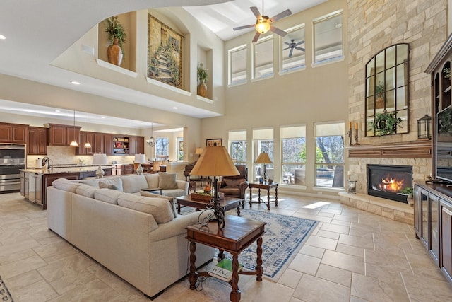 5131 Rowley Falls Ln, Sugar Land, TX 77479 - living area featuring a ceiling fan, plenty of natural light, a stone fireplace, stone tile flooring, and a towering ceiling