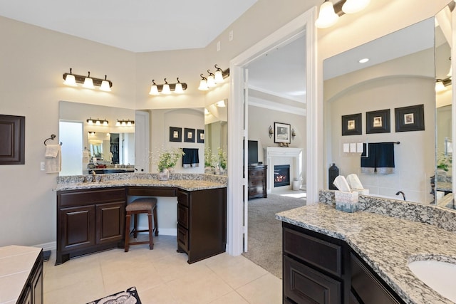5131 Rowley Falls Ln, Sugar Land, TX 77479 - bathroom featuring a warm lit fireplace, tile patterned floors, two vanities, and baseboards
