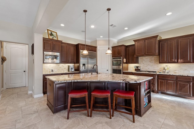 5131 Rowley Falls Ln, Sugar Land, TX 77479 - kitchen featuring built in appliances, a sink, tasteful backsplash, a large island with sink, and dark brown cabinetry