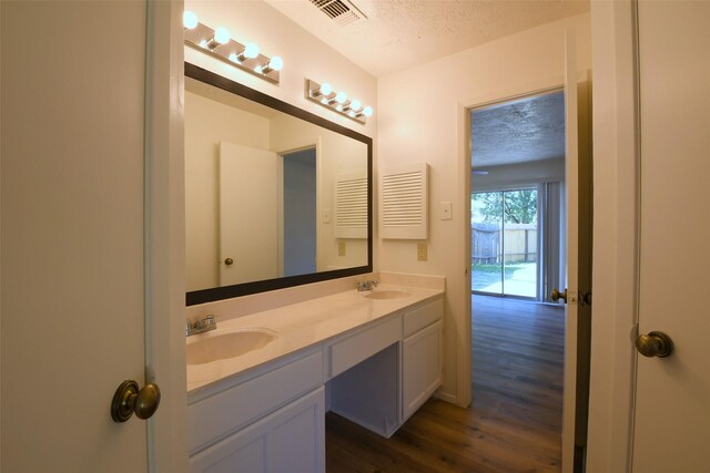 18811 Pine Trace Ct, Humble, TX 77346 - bathroom featuring a textured ceiling, wood finished floors, double vanity, and baseboards