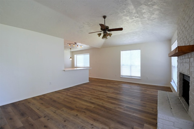 18811 Pine Trace Ct, Humble, TX 77346 - unfurnished living room featuring a brick fireplace, a ceiling fan, dark wood-style floors, a textured ceiling, and baseboards