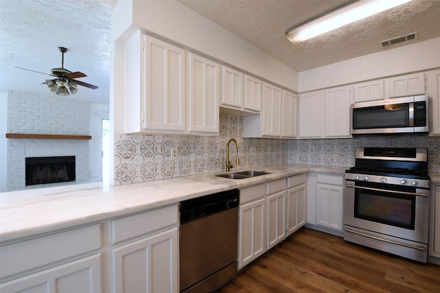 18811 Pine Trace Ct, Humble, TX 77346 - kitchen with appliances with stainless steel finishes, a sink, a textured ceiling, and white cabinets