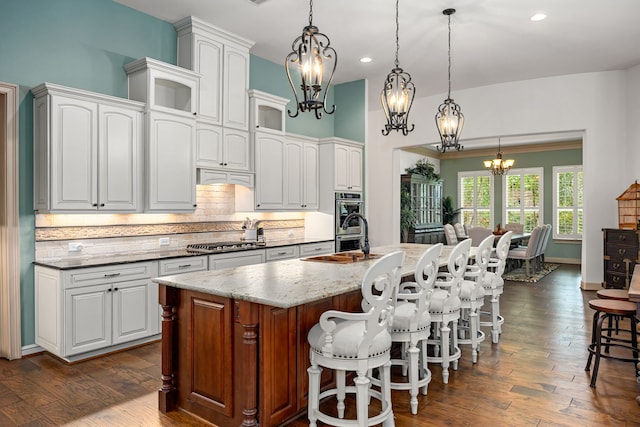 1223 Eversham Way, Kingwood, TX 77339 - kitchen featuring a chandelier, stainless steel appliances, tasteful backsplash, dark wood finished floors, and recessed lighting