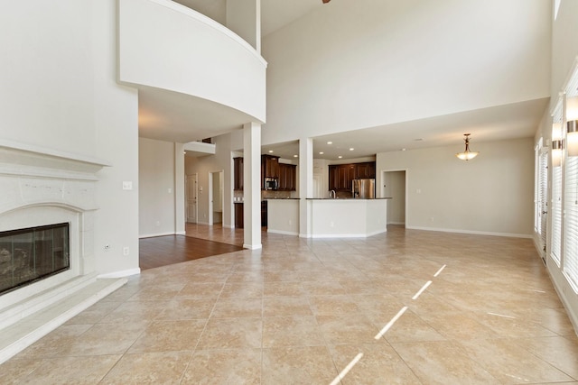 10410 Kingston Creek Ln, Cypress, TX 77433 - unfurnished living room featuring a towering ceiling, a premium fireplace, light tile patterned floors, and baseboards
