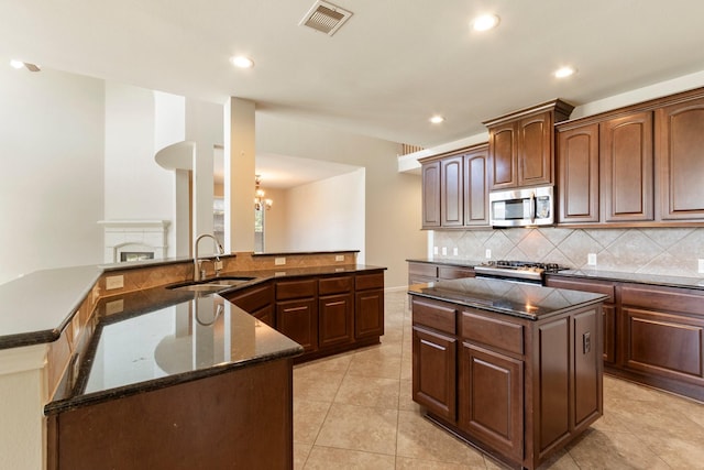 10410 Kingston Creek Ln, Cypress, TX 77433 - kitchen with a sink, stainless steel microwave, a center island with sink, tasteful backsplash, and recessed lighting