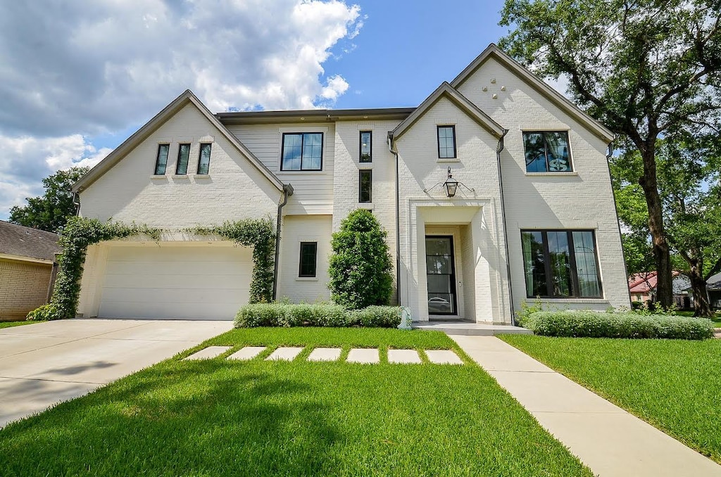 13802 Saint Marys Ln, Houston, TX 77079 - view of front of property featuring a garage, brick siding, a front yard, and driveway