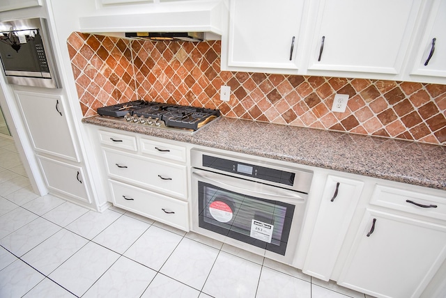 3119 Wagon Trail Dr, Sugar Land, TX 77479 - kitchen with appliances with stainless steel finishes, extractor fan, white cabinets, and light stone counters