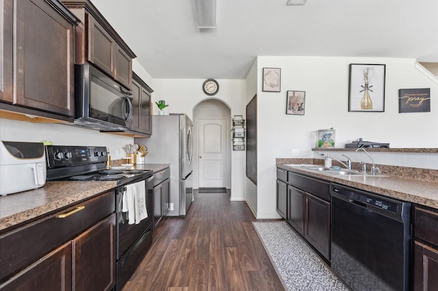 2415 Fallen Pine Ln, Houston, TX 77088 - kitchen with black appliances, a sink, dark brown cabinetry, dark wood-style floors, and arched walkways