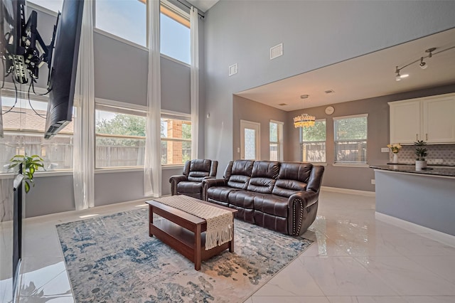 5615 Gemstone Park Rd, Richmond, TX 77407 - living room with a high ceiling, baseboards, light marble finish flooring, and rail lighting