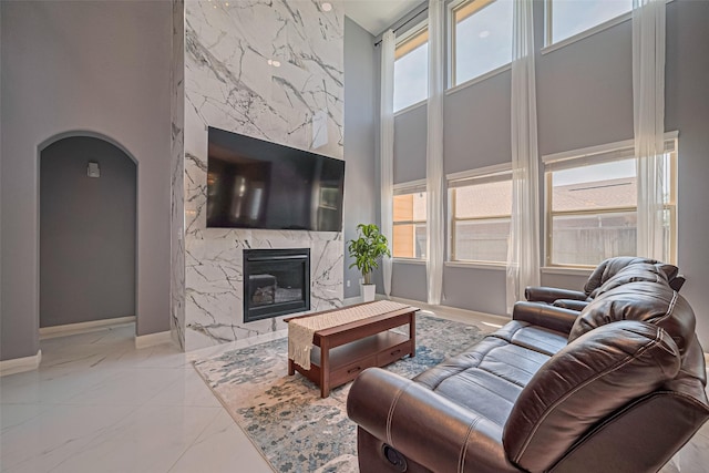 5615 Gemstone Park Rd, Richmond, TX 77407 - living room with marble tiled flooring, healthy amount of natural light, arched walkways, baseboards, and a towering ceiling