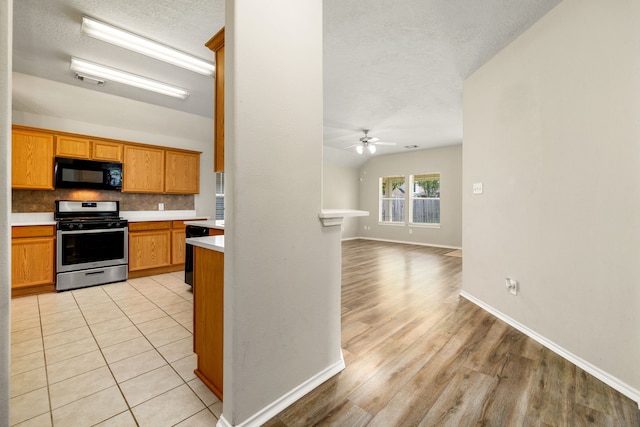 6733 Hidden Colony Ln, Dickinson, TX 77539 - kitchen featuring gas stove, black microwave, light countertops, a ceiling fan, and a textured ceiling