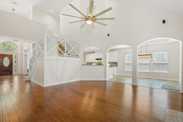 5122 Hidden Brook Ln, League City, TX 77573 - unfurnished living room featuring a high ceiling, a ceiling fan, wood-type flooring, stairway, and arched walkways