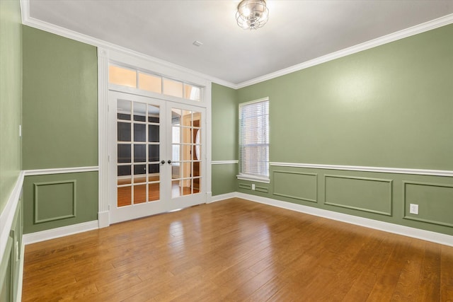 5122 Hidden Brook Ln, League City, TX 77573 - empty room featuring french doors, crown molding, a decorative wall, wood finished floors, and wainscoting