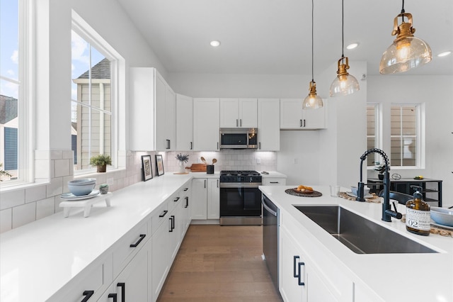 8303 Springwood Creek Ln, Houston, TX 77055 - kitchen featuring appliances with stainless steel finishes, white cabinetry, decorative light fixtures, tasteful backsplash, and light wood finished floors