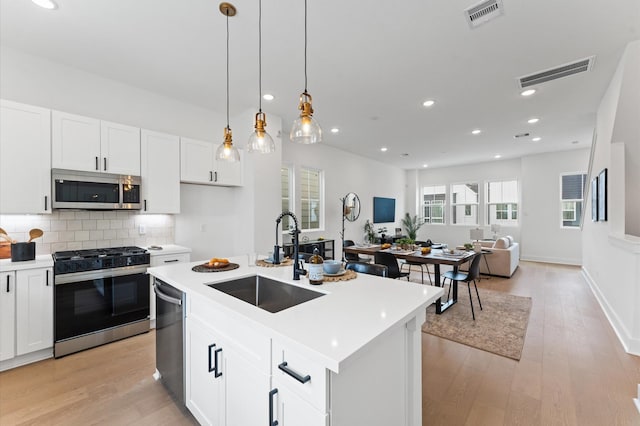 8303 Springwood Creek Ln, Houston, TX 77055 - kitchen featuring appliances with stainless steel finishes, open floor plan, light wood-style floors, white cabinetry, and light countertops