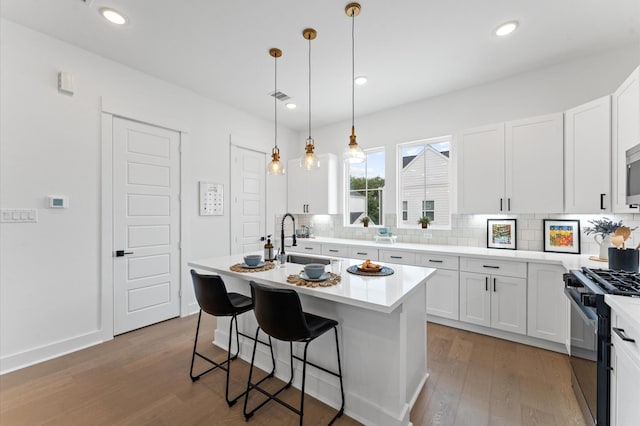 8303 Springwood Creek Ln, Houston, TX 77055 - kitchen with black gas range, tasteful backsplash, wood finished floors, a kitchen breakfast bar, and recessed lighting