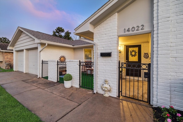 14022 Roundstone Ln, Houston, TX 77015 - exterior entry at dusk with a gate, brick siding, and a shingled roof