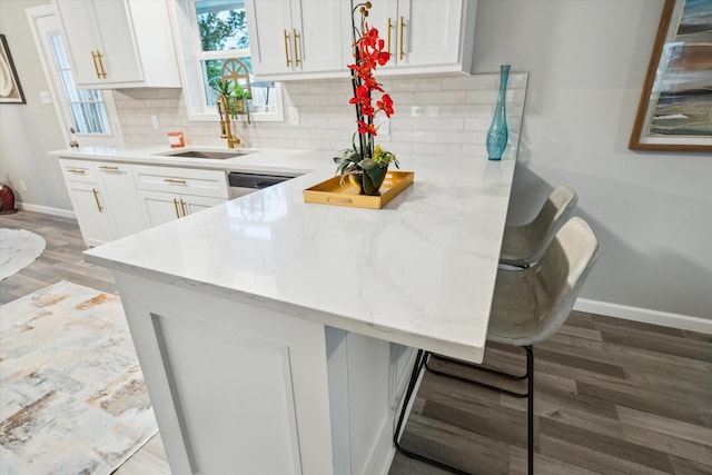 14022 Roundstone Ln, Houston, TX 77015 - kitchen with a breakfast bar area, baseboards, white cabinets, wood finished floors, and a peninsula