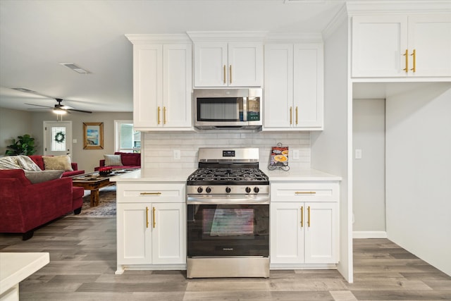 14022 Roundstone Ln, Houston, TX 77015 - kitchen with appliances with stainless steel finishes, decorative backsplash, white cabinetry, and light wood-type flooring