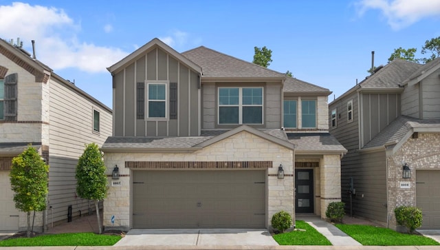 8957 Monterey View Dr, Houston, TX 77080 - view of front facade with board and batten siding, roof with shingles, stone siding, a garage, and driveway