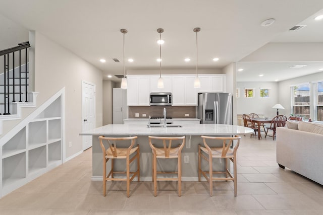 8957 Monterey View Dr, Houston, TX 77080 - kitchen featuring stainless steel appliances, white cabinetry, tasteful backsplash, a sink, and a center island with sink