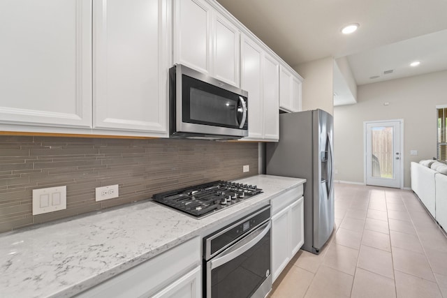 8957 Monterey View Dr, Houston, TX 77080 - kitchen with stainless steel appliances, white cabinetry, light tile patterned floors, tasteful backsplash, and recessed lighting