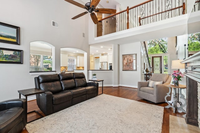 11802 Guernsey Dr, Tomball, TX 77377 - living room featuring arched walkways, a high ceiling, dark wood finished floors, a ceiling fan, and baseboards