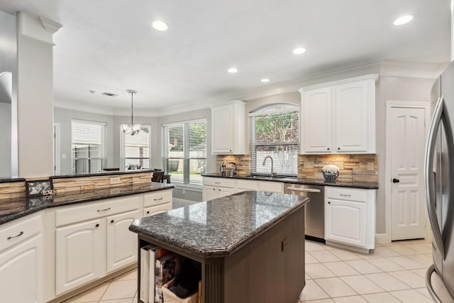 11802 Guernsey Dr, Tomball, TX 77377 - kitchen featuring stainless steel appliances, a sink, light tile patterned flooring, crown molding, and white cabinetry