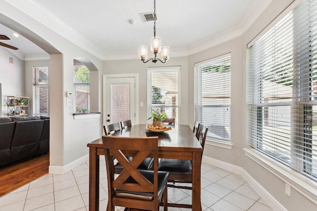 11802 Guernsey Dr, Tomball, TX 77377 - dining room with light tile patterned floors, a chandelier, crown molding, baseboards, and arched walkways