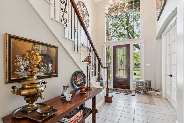 11802 Guernsey Dr, Tomball, TX 77377 - foyer entrance with a chandelier, a high ceiling, stairs, light tile patterned flooring, and baseboards