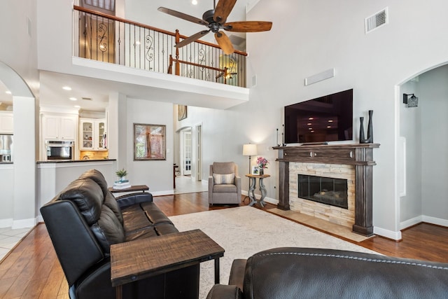 11802 Guernsey Dr, Tomball, TX 77377 - living room with arched walkways, hardwood / wood-style floors, a ceiling fan, a high ceiling, and baseboards