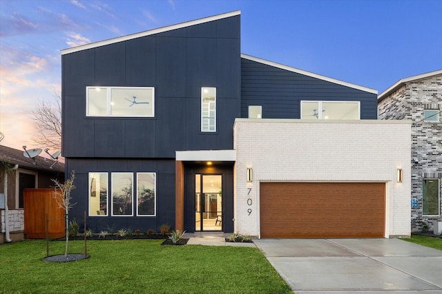 709 Moody St, Houston, TX 77009 - modern home featuring concrete driveway, a garage, a yard, and brick siding