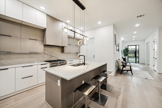 709 Moody St, Houston, TX 77009 - kitchen with a sink, modern cabinets, light wood finished floors, backsplash, and an island with sink