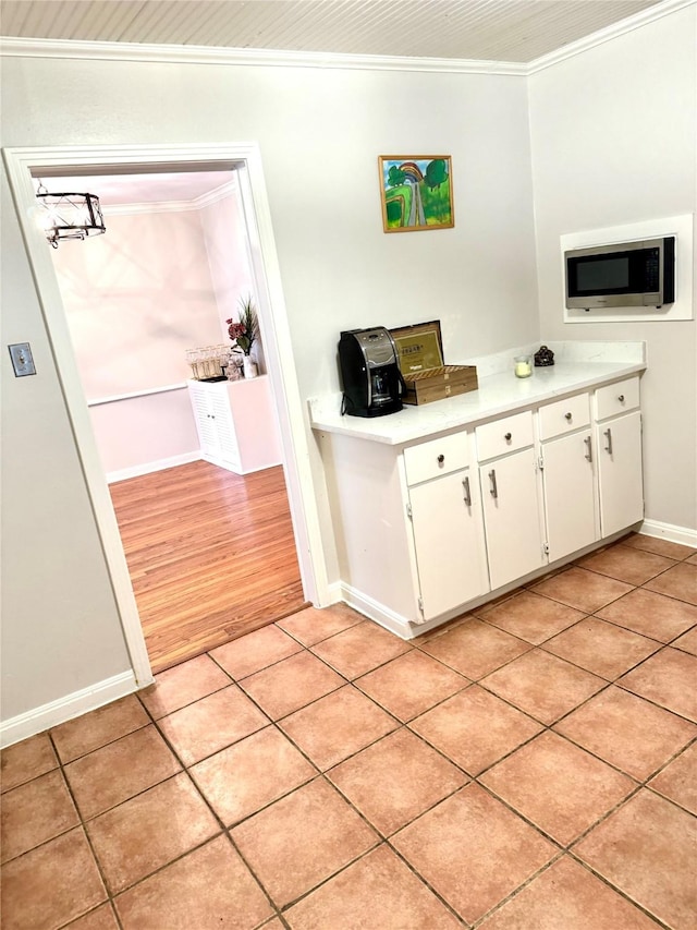 1062 Lamonte Ln, Houston, TX 77018 - kitchen featuring stainless steel microwave, crown molding, light countertops, white cabinetry, and light tile patterned floors