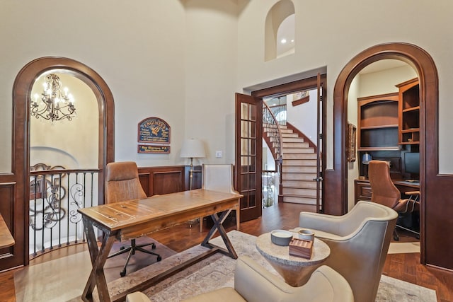14 Royal King Rd, Tomball, TX 77377 - home office featuring wood finished floors, a chandelier, arched walkways, and a towering ceiling