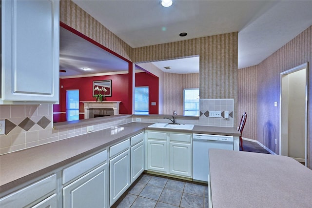 kitchen featuring a sink, wallpapered walls, dishwasher, decorative backsplash, and white cabinets