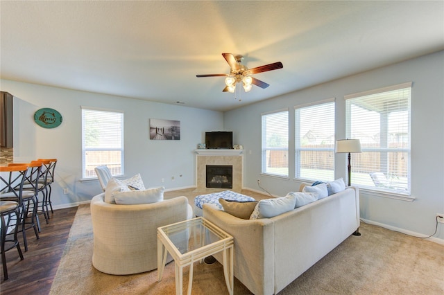 living room with plenty of natural light, ceiling fan, a tile fireplace, and baseboards