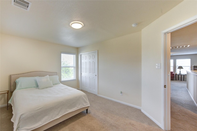 bedroom with light colored carpet, a closet, and baseboards