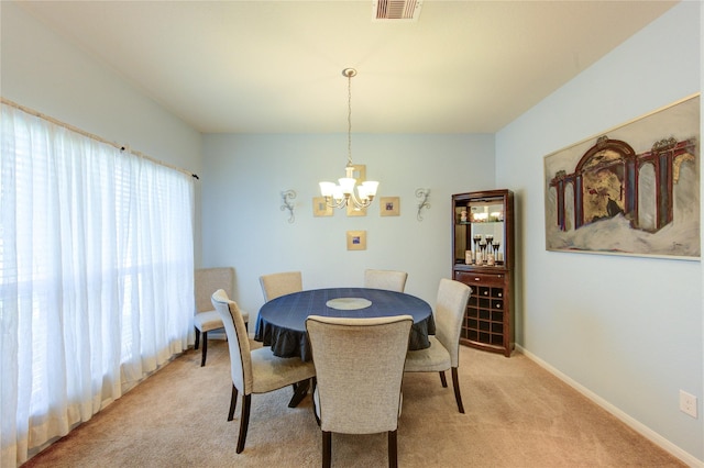 dining room featuring a chandelier, light carpet, and baseboards