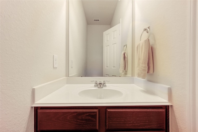 bathroom with a textured wall and vanity