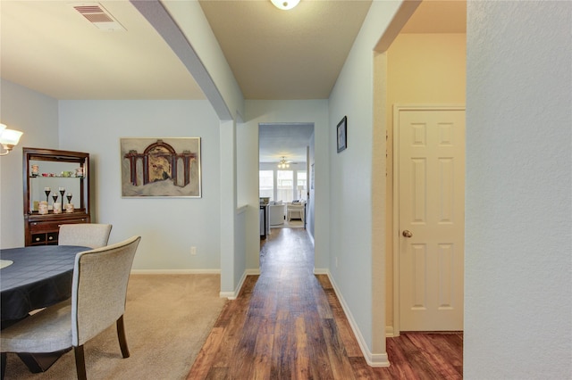 hall featuring arched walkways, wood finished floors, and baseboards
