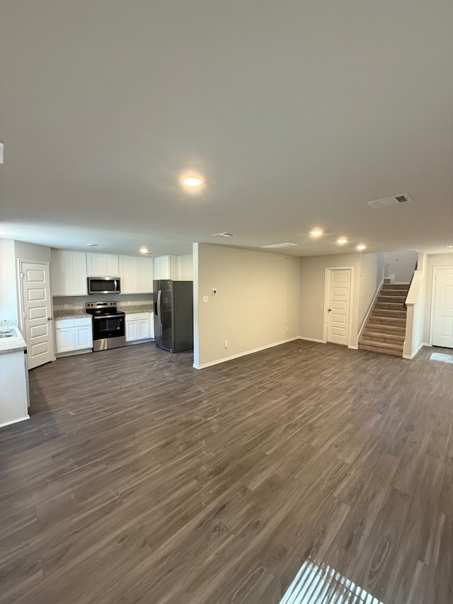 22711 American Kestrel Ct, Splendora, TX 77372 - unfurnished living room featuring stairway, dark wood-style flooring, recessed lighting, baseboards, and a sink