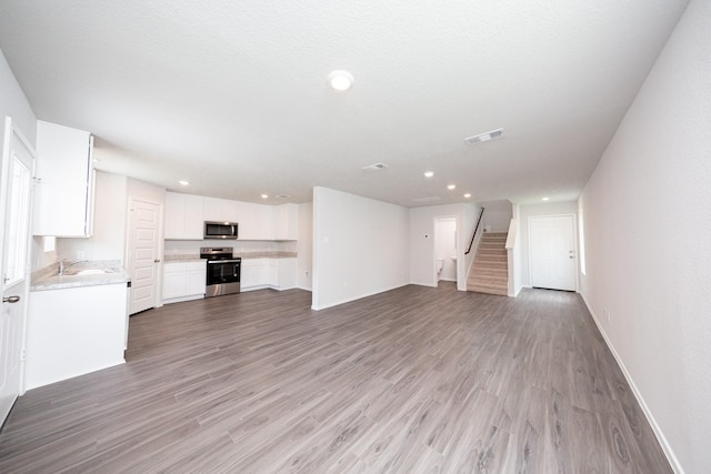 22711 American Kestrel Ct, Splendora, TX 77372 - unfurnished living room with stairs, light wood-style flooring, and recessed lighting