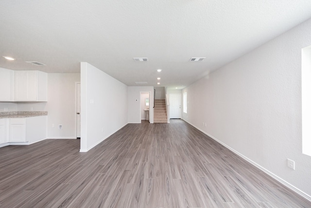 22711 American Kestrel Ct, Splendora, TX 77372 - unfurnished living room featuring wood finished floors, stairs, and recessed lighting