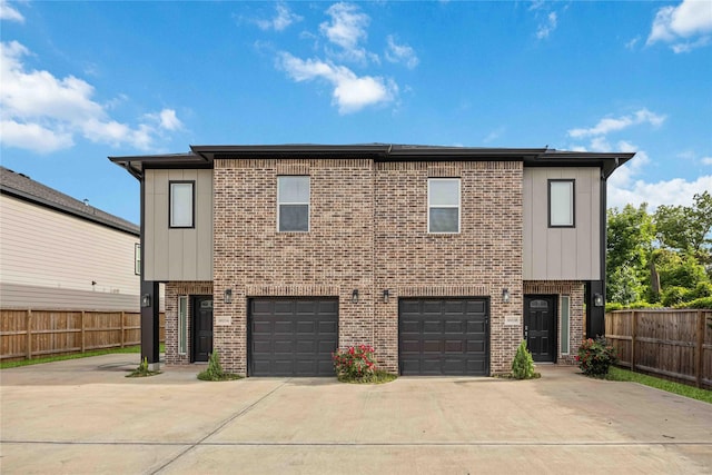 5023 Mallow St A/B, Unit A/B Houston, TX 77033 - view of front facade featuring brick siding, concrete driveway, fence, an attached garage, and board and batten siding
